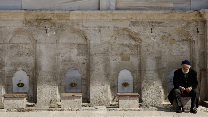 A worshipper waits in front of the locked Fatih Mosque for the Friday prayers as Turkey suspended mass prayers in mosques nationwide until the risk of coronavirus disease (COVID-19) passes in Istanbul,Turkey March 20, 2020. REUTERS/Umit Bektas - RC2PNF9ARP7Q