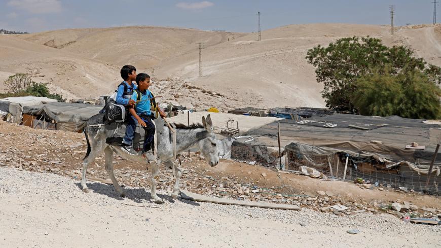 Palestinian Bedouin pupils ride a donkey on their way to school in the village of Khan al-Ahmar in the Israeli-occupied West Bank on September 6, 2018, after Israel's top court upheld an order to raze the village. - Israel's top court on Wednesday upheld an order to raze a Palestinian Bedouin village in the occupied West Bank, after debating petitions challenging the decision. "We reject the petitions" against the directive to demolish Khan al-Ahmar, the supreme court panel said in its ruling, adding that a