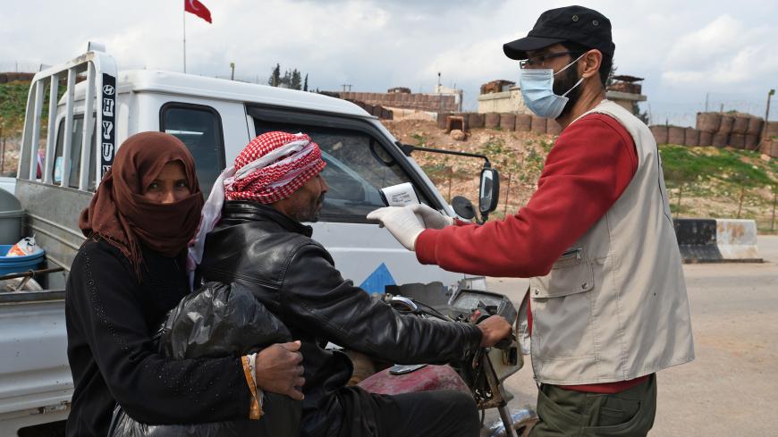 Local groups in cooperation with the Turkish health department measure people's temperatures and inform them about the dangers of the spread of the coronavirus, on March 17, 2020 near the camp for displaced Syrians in Deir al-Ballut camp in Afrin's countryside in the northern Syrian province of Aleppo, along the border with Turkey. (Photo by Rami al SAYED / AFP) (Photo by RAMI AL SAYED/AFP via Getty Images)