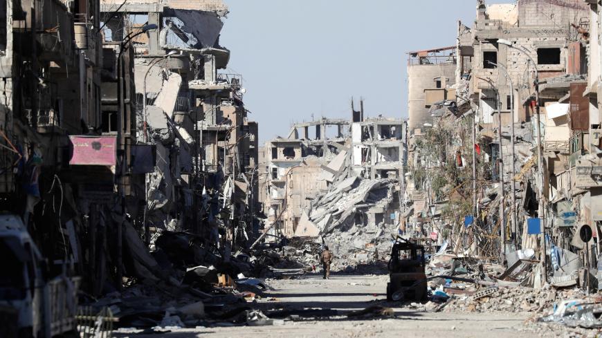 A fighter of Syrian Democratic Forces stands amidst the ruins of buildings near the Clock Square in Raqqa, Syria October 18, 2017. Picture taken October 18, 2017. REUTERS/Erik De Castro - RC1E4E003870