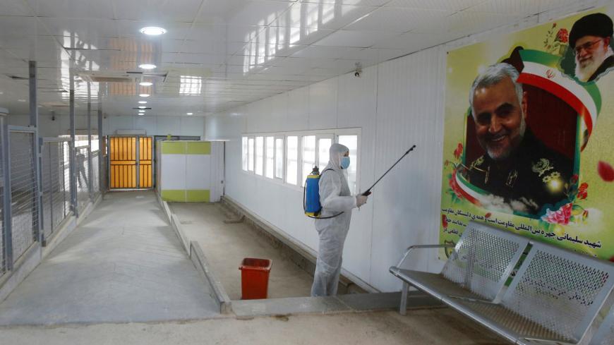 A worker in a protective suit sprays a disinfectant inside the gate of Shalamcha Border Crossing, after Iraq shut a border crossing to travellers between Iraq and Iran, Iraq March 8, 2020. REUTERS/Essam al-Sudani - RC2MFF94758Q