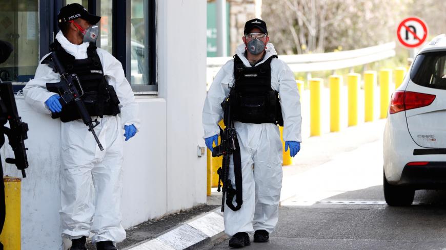 Israeli border policemen wearing protective gear as a precaution against the coronavirus, guard at an Israeli checkpoint in the occupied West Bank on the outskirts of Jerusalem March 11, 2020. REUTERS/Ronen Zvulun - RC2MHF9K85OW