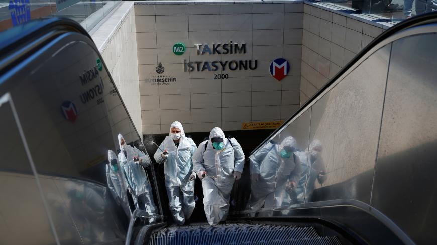 Municipality workers in protective suits disinfect entrance of Taksim metro station in central Istanbul, Turkey, March 17, 2020. REUTERS/Kemal Aslan - RC2ULF95LNH1