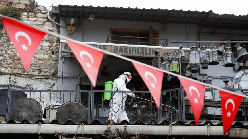 A worker in a protective suit sprays disinfectant at Grand Bazaar, known as the Covered Bazaar, to prevent the spread of coronavirus disease (COVID-19), in Istanbul, Turkey, March 25, 2020. REUTERS/Umit Bektas - RC2YQF9I7XRJ