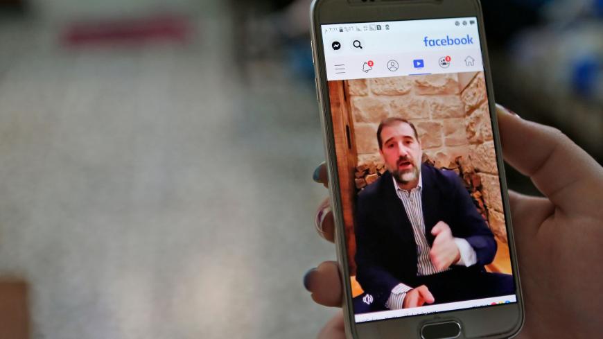 A woman watches the Facebook video of Syrian businessman Rami Makhlouf on her mobile in Syria's capital Damascus, on May 11, 2020. - Syria's top tycoon publicly airing his grievances has revealed a power struggle within the ruling family as it tries to cement its power after nine years of war, analysts say. After years of staying out of the limelight, business magnate Rami Makhlouf this month in two videos on Facebook laid bare his struggles with the regime headed by his first cousin President Bashar al-Ass