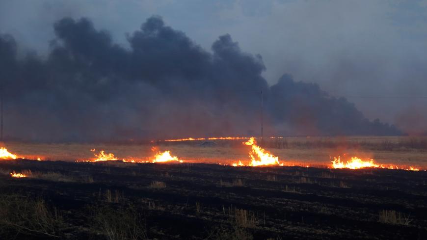 A fire and smoke rises from a wheat field on the outskirts of Mosul, Iraq June 15, 2019. Picture taken June 15, 2019. REUTERS/Abdullah Rashid - RC1C2370E800