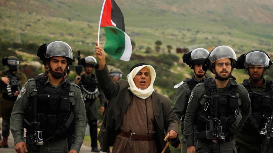 A demonstrator holding a Palestinian flag stands amongst Israeli border police members during a protest against Israeli settlements and the U.S. President Donald Trump's Middle East peace plan, in Jordan Valley in the Israeli-occupied West Bank February 25, 2020. REUTERS/Raneen Sawafta - RC2O7F96E3FQ