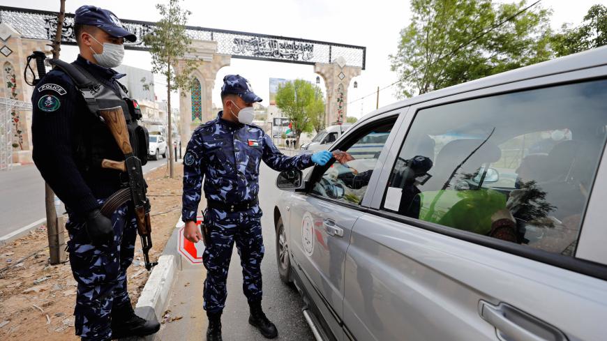 Palestinian police officers check the identity card of a vehicle's occupant during a home-confinement order to prevent the spread of the coronavirus disease (COVID-19), in Hebron in the Israeli-occupied West Bank, April 7, 2020. Picture taken April 7, 2020. REUTERS/Mussa Qawasma - RC2X0G91R5K3