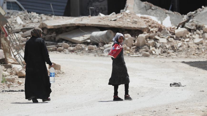 A girl holds a bag as she walks near the rubble of damaged buildings in the rebel-held town of Nairab, Idlib region, Syria April 17, 2020. Picture taken April 17, 2020. REUTERS/Khalil Ashawi - RC2C8G95MW34