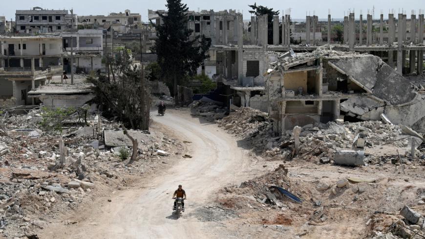 A man rides a motorbike past damaged buildings in the rebel-held town of Nairab, Idlib region, Syria April 17, 2020. Picture taken April 17, 2020.  REUTERS/Khalil Ashawi - RC2C8G9K3BBG