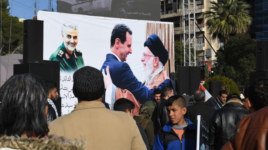Syrian demonstrators look at a poster bearing the portraits of Iran's Supreme Leader Ayatollah Ali Khamenei (C-R) and Syrian President Bashar al-Assad (C) in the central Saadallah al-Jabiri square in the northern Syrian city of Aleppo on January 7, 2020, to mourn and condemn the death of Iranian military commander Qasem Soleimani (portrait-L), and nine others in a US air strike in Baghdad. (Photo by - / AFP) (Photo by -/AFP via Getty Images)
