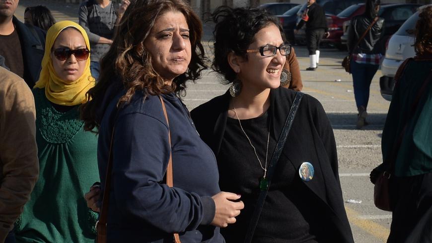 The sister (R) of Egyptian rights activist Sanaa Seif stands outside a court in Cairo on December 28, 2014, along with friends and relatives of the twenty-two other pro-democracy activists accused of holding an illegal protest last June, after an appeals court reduced the jail sentences from three years to two. The defendants were accused of holding an illegal protest on June 21 calling for the release of detainees and the annulment of a law that bans all but police-sanctioned demonstrations. They were also