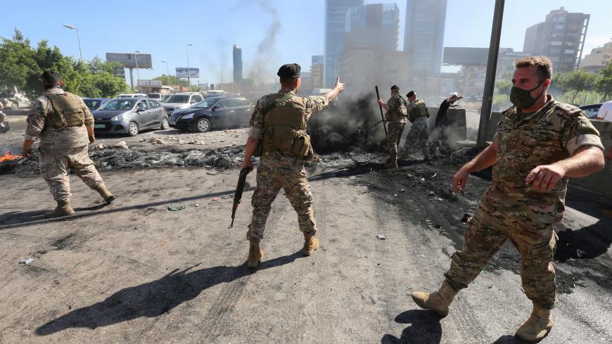 Lebanese army soldiers open a road that was blocked by demonstrators during a protest sparked by a rapid fall in the pound currency and mounting economic hardship, along a highway in Antelias, Lebanon June 12, 2020. REUTERS/Aziz Taher - RC2K7H9DQBEB