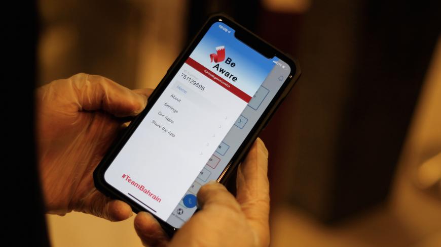 A man wearing protective gloves checks the app "Be Aware", launched by Bahrain's health authorities to contain the coronavirus disease (COVID-19) by spreading awareness and sharing updates on the situation, at a hotel in Manama, Bahrain, April 19, 2020. Picture taken April 19, 2020. REUTERS/Hamad I Mohammed - RC278G9BMSM2