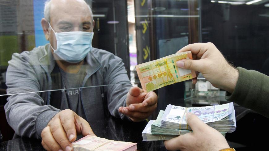 A man wearing a face mask takes Lebanese pound banknotes at a currency exchange shop in Beirut, Lebanon April 24, 2020. REUTERS/Mohamed Azakir - RC20BG9T3QWR