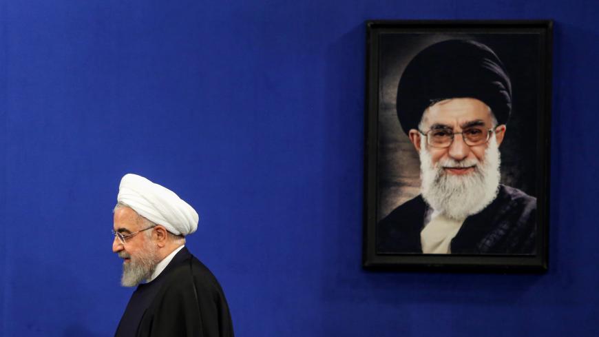 Iranian President Hassan Rouhani walks past a portrait of Supreme Leader Ayatollah Ali Khamenei as he arrives for a news conference in the capital Tehran, on February 16, 2020. - Iran's President Hassan Rouhani ruled out resigning and vowed to see out his term, even as he admitted he had offered to step aside twice since being elected. Speaking ahead of a general election next Friday, Rouhani also appealed to voters to turn out despite the fact that many moderate and reformist candidates were disqualified f