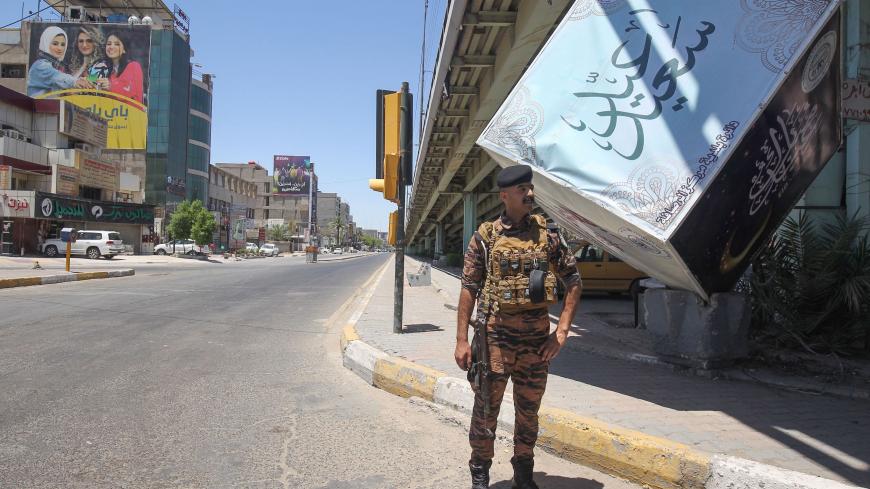 Iraqi security forces stand guard at a checkpoint enforcing a curfew due to the COVID-19 coronavirus pandemic during the Eid al-Fitr holiday which marks the end of the holy month of Ramadan, in Baghdad on May 26, 2020. (Photo by AHMAD AL-RUBAYE / AFP) (Photo by AHMAD AL-RUBAYE/AFP via Getty Images)