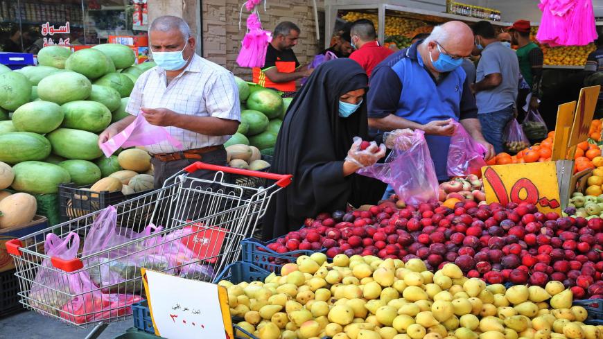 Iraqis, some wearing a protective mask amid the COVID-19 pandemic, buy fresh produce from a street seller at a market in Karrada, in the capital Baghdad, on July 14, 2020. - Iraq, in a bid to prevent the spread of the deadly COVID-19 illness, shut its 32 border crossings to goods and people coming from Iran, Turkey, Syria, Jordan and Saudi Arabia in mid-March, which helped its agriculture ministry accelerate a campaign to make Iraqi food markets self-sustainable, after years of relying on foreign imports fo