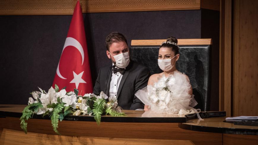 ISTANBUL, TURKEY - JULY 01: Groom Okan Barut and bride Oya Kulaksiz wear face masks as they take part in their wedding ceremony at the Kadikoy Municipality marriage office on July 01, 2020 in Istanbul, Turkey. Restrictions on Turkish wedding halls were lifted on July 01, 2020 after being closed for months due to the Coronavirus pandemic. Turkey continues to slowly ease restrictions after recently reopening, cafes, restaurants, parks and inter-city travel. (Photo by Chris McGrath/Getty Images)