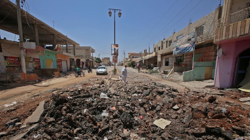 A Syrian civilian walks past a shell hole after Syrian government forces recently recaptured the village of Ghariyah ash Sharqiyah from the rebels, in the province of Daraa, on July 4, 2018. - Syrian rebels were facing a deadline Wednesday in negotiations with regime ally Russia to either agree to tough surrender terms in the south or come under a renewed military onslaught. (Photo by Youssef KARWASHAN / AFP)        (Photo credit should read YOUSSEF KARWASHAN/AFP via Getty Images)