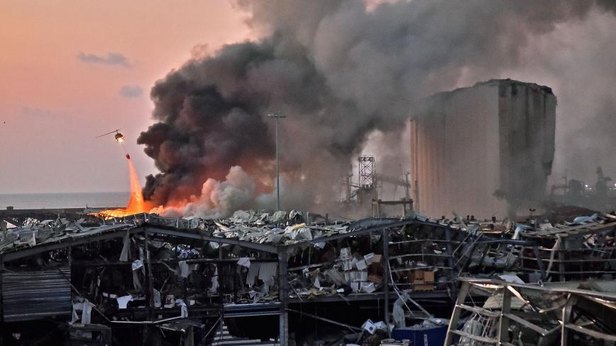 TOPSHOT - EDITORS NOTE: Graphic content / A helicopter puts out a fire at the scene of an explosion at the port of Lebanon's capital Beirut on August 4, 2020. (Photo by STR / AFP) (Photo by STR/AFP via Getty Images)