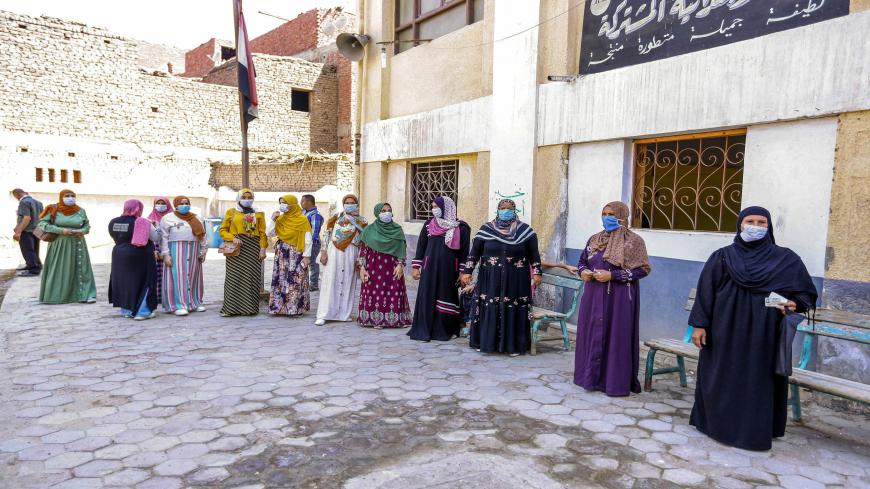 Women, mask-clad due to the COVID-19 coronavirus pandemic, wait to cast their ballots outside a polling station in the town of el-Ayyat in Giza province south of the Egyptian capital on August 11, 2020 for candidates running in the upper house election for the newly created Senate. - The two-day vote for 200 of the Senate's 300 seats will be largely contested by candidates who back President Abdel Fattah al-Sisi, who has quietened most opposition within and outside the legislature. (Photo by - / AFP) (Photo