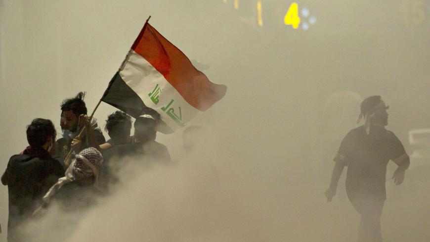 TOPSHOT - Iraqi demonstrators gather amid smoke after fire services extinguished fire on tires during a protest near the governor's residence in the southern city of Basra, to oppose  assassinations and demand the resignation of top security officials in the southern Iraqi governorate, on August 17, 2020. (Photo by Hussein FALEH / AFP) (Photo by HUSSEIN FALEH/AFP via Getty Images)