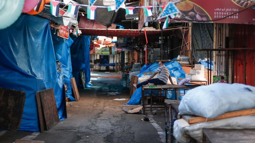 A Palestinian man sits on an empty stall at the closed-down Fras market in Gaza City, amid a two-day lockdown due to the detection of first cases of COVID-19 in the general population, on August 25, 2020. (Photo by MAHMUD HAMS / AFP) (Photo by MAHMUD HAMS/AFP via Getty Images)
