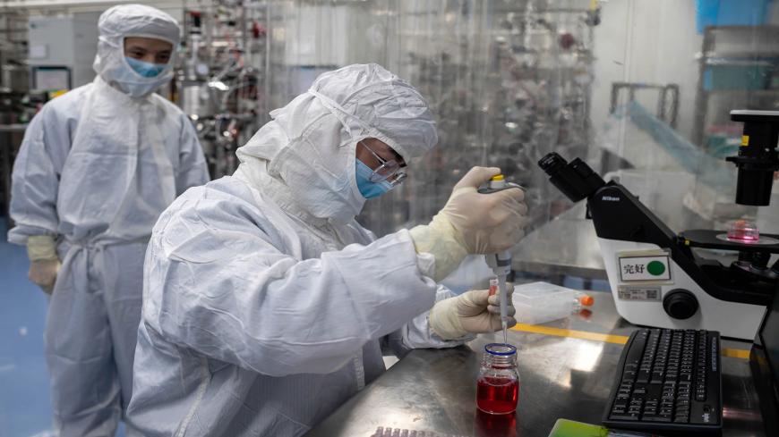 In this picture taken on April 29, 2020, an engineer takes samples of monkey kidney cells as he make tests on an experimental vaccine for the COVID-19 coronavirus inside the Cells Culture Room laboratory at the Sinovac Biotech facilities in Beijing. - Sinovac Biotech, which is conducting one of the four clinical trials that have been authorised in China, has claimed great progress in its research and promising results among monkeys. (Photo by NICOLAS ASFOURI / AFP) / TO GO WITH Health-virus-China-vaccine,FO