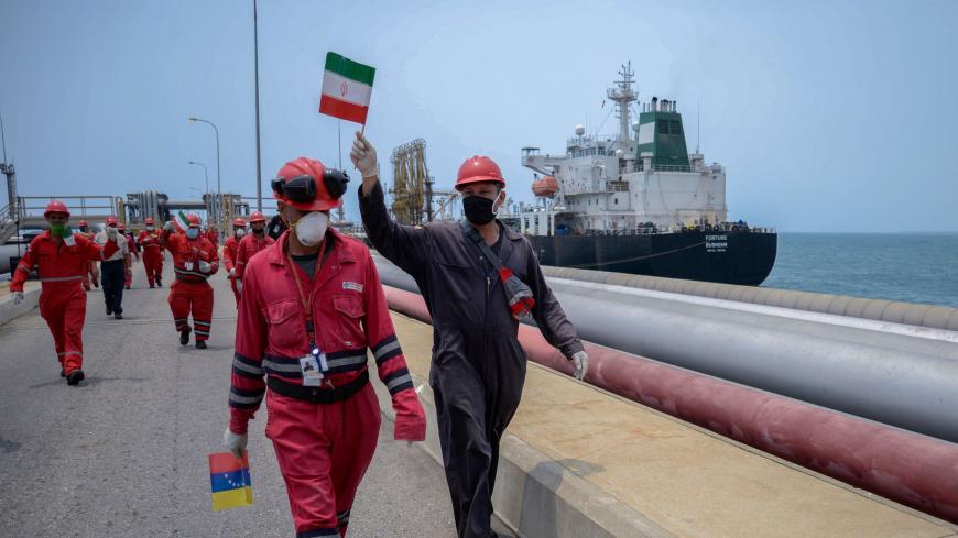 TOPSHOT - A worker of the Venezuelan state oil company PDVSA waves an Iranian flag as the Iranian-flagged oil tanker Fortune docks at the El Palito refinery in Puerto Cabello, in the northern state of Carabobo, Venezuela, on May 25, 2020. - The first of five Iranian tankers carrying much-needed gasoline and oil derivatives docked in Venezuela on Monday, Caracas announced amid concern in Washington over the burgeoning relationship between countries it sees as international pariahs. (Photo by - / AFP) (Photo 