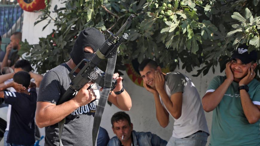 Palestinians cover their ears as a masked man fires a volley from his rifle, during the funeral of Dalia Ahmed Suleiman Samudi, 23, in Jenin city in the occupied West Bank on August 7, 2020, who was killed by Israeli fire during clashes. - Samudi died of a gunshot wound after being shot near the site of clashes between Palestinian youths and Israeli troops in the occupied West Bank, Palestinian officials said. (Photo by JAAFAR ASHTIYEH / AFP) (Photo by JAAFAR ASHTIYEH/AFP via Getty Images)