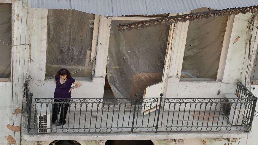 A woman watches as rescue workers gather at damaged building in Lebanon's capital Beirut, in search of possible survivors from a mega-blast at the adjacent port one month ago, after scanners detected a pulse, on September 4, 2020. - Lebanese rescuers scoured rubble for a possible survivor in Beirut after the detection of a pulse drew crowds hopeful of a miracle one month on from a devastating explosion. (Photo by JOSEPH EID / AFP) (Photo by JOSEPH EID/AFP via Getty Images)