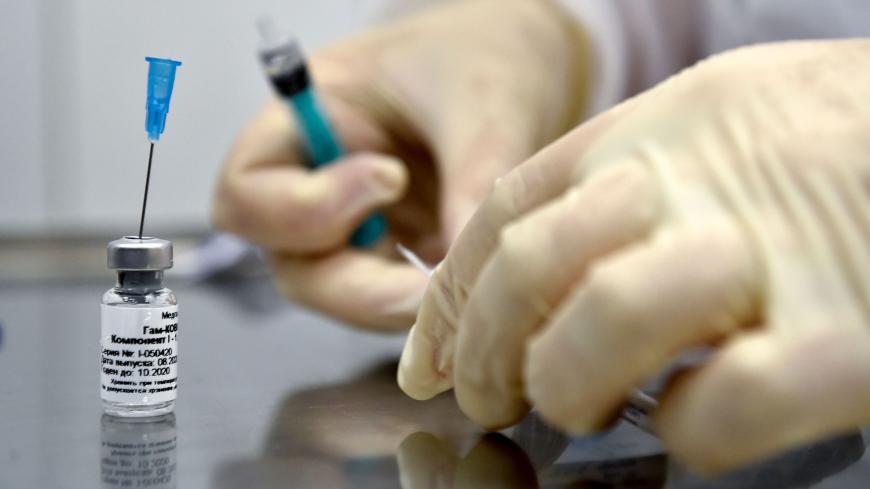 A nurse prepares to inoculate volunteer Ilya Dubrovin, 36, with Russia's new coronavirus vaccine in a post-registration trials at a clinic in Moscow on September 10, 2020. - Russia announced last month that its vaccine, named "Sputnik V" after the Soviet-era satellite that was the first launched into space in 1957, had already received approval. The vaccine was developed by the Gamaleya research institute in Moscow in coordination with the Russian defence ministry. (Photo by Natalia KOLESNIKOVA / AFP) (Phot