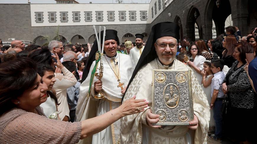 Catholic believers and clerics gather outside Greek-Melkite Patriarchal Cathedral of the Dormition of Our Lady to mark Palm Sunday in the capital Damascus in Bab Sharki, Old Damascus on April 14, 2019. (Photo by LOUAI BESHARA / AFP) (Photo credit should read LOUAI BESHARA/AFP via Getty Images)