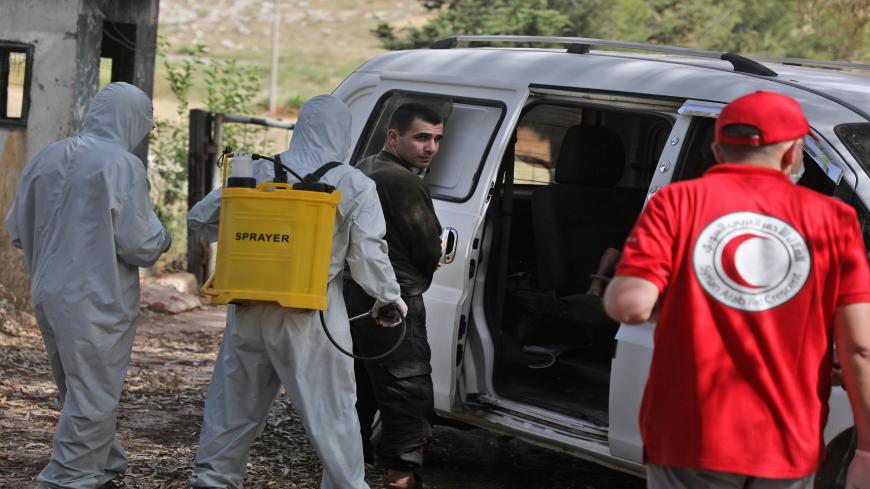 A fighter from the Hayat Tahrir al-Sham group is sprayed with decontamination liquid upon his release in a reported prisoner swap deal with regime forces in the town of Darret Ezza, about 30 kilometres northwest of the northern Syrian city of Aleppo on May 16, 2020. (Photo by AAREF WATAD / AFP) (Photo by AAREF WATAD/AFP via Getty Images)
