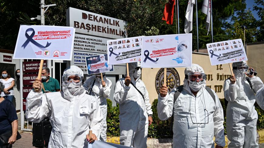 Health workers and doctors wearing personal protective equipment (PPE) hold placards reading "You cannot manage, we are dying - We are running out" during a demostration against goverments health policy on September 15, 2020 in front of Istanbul University medical faculty. (Photo by Ozan KOSE / AFP) (Photo by OZAN KOSE/AFP via Getty Images)