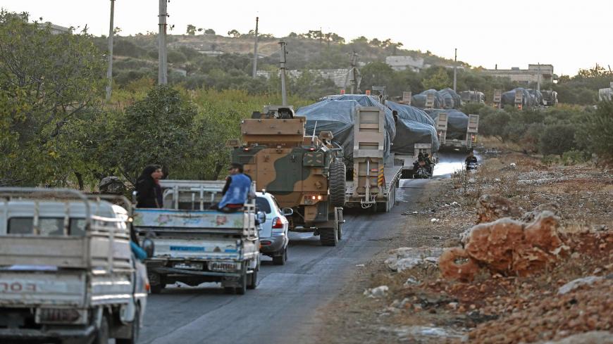 Civilians drive along a road behind a Turkish military convoy through the village of Iblin, near Ariha in Syria's rebel-held northwestern Idlib province on October 20, 2020 after Turkish forces vacated the Morek post in Hama's countryside. - Turkey started withdrawing from one of its largest outposts in northwest Syria encircled for the past year by Syrian regime forces, a war monitor and a pro-Ankara rebel commander said. The outpost in Morek is Turkey's largest in the northwest province of Hama, which is