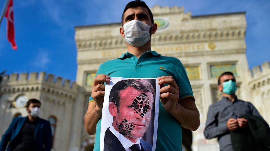 A man holds a picture of Macron with a shoe print on it as Turkish protesters shout slogans against France during a demonstration against French President's comments over Prophet Muhammad cartoons, in Istanbul, on October 25, 2020. - Turkish President Recep Tayyip Erdogan on October 25, 2020 renewed his call for his French counterpart Emmanuel Macron to undergo mental checks, a day after his comments prompted Paris to recall its envoy to Ankara. Macron's comments, on October 21, 2020, came in response to th