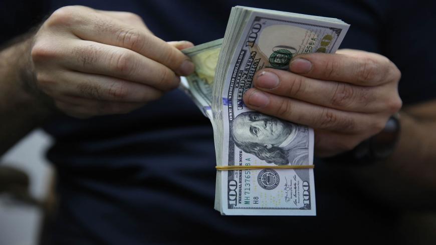 A man counts a pile of US Dollar bank notes in the Iraqi capital Baghdad on May 4, 2020, during the novel coronavirus pandemic crisis. - With its financial outlook darkening by the day, Iraq is considering slashing its massive public payroll -- an unpopular move likely to renew protests.
OPEC's second-largest producer has been hit hard by the double-whammy of collapsed crude prices and the COVID-19 pandemic, which have hacked at its revenues from oil sales. (Photo by AHMAD AL-RUBAYE / AFP) (Photo by AHMAD A