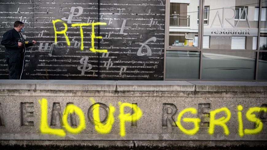 An employee cleans an outside wall of the National Armenian Memorial Centre in Decines-Charpieu, near Lyon, on November 1, 2020 where pro-Turkish yellow letters graffiti tags have been painted overnight. - Inscriptions read "RTE" which can refers to Turkish Prime minister Recep Tayyip Erdogan and "Grey Wolf" (Loup Gris), the name of an ultra-nationalist movement in Turkey. A nearby memorial for the Armenian genocide have also been tagged with the words "Fuck Armenia". (Photo by JEFF PACHOUD / AFP) (Photo by