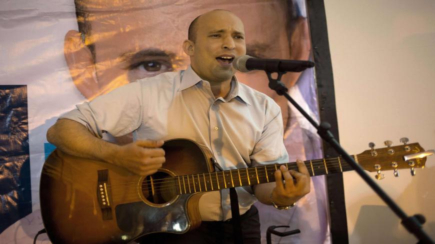 Israeli Economy Minister and head of the right-wing Jewish Home party, Naftali Bennett plays the guitar and sings during an election campaign gathering for the Jewish community in Kibbutz Kfar Etzion in the Gush Etzion settlement block in the West Bank, on March 12, 2015, ahead of a snap general election scheduled March 17. Bennett, 42, is a champion of the settler movement and a key challenger of Netanyahu to head Israel's rightwing. AFP PHOTO / MENAHEM KAHANA (Photo credit should read MENAHEM KAHAN