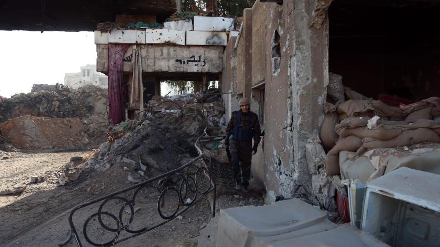 A rebel fighter from the Ahrar al-Sham brigade walks past the debris of damaged buildings in the rebel-held besieged town of Harasta, in the Eastern Ghouta region on the outskirts of Damascus, on November 16, 2017. / AFP PHOTO / ABDULMONAM EASSA        (Photo credit should read ABDULMONAM EASSA/AFP via Getty Images)