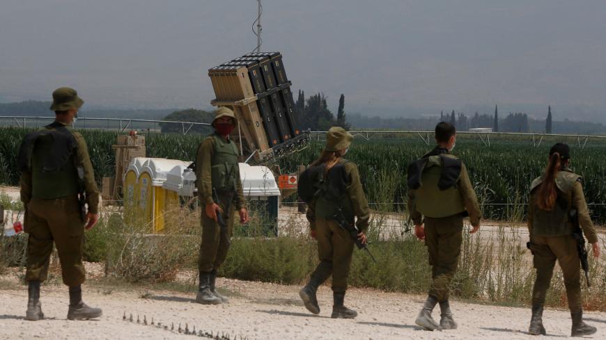 Israeli soldiers stand in front of an Iron Dome defence system battery, designed to intercept and destroy incoming short-range rockets and artillery shells, in the Hula Valley in northern Israel near the border with Lebanon, on July 27, 2020. - On either side of the Israeli-Lebanese border, the language is military: The Lebanese Hezbollah movement asserts that anti-Israel action is "irremediable", Israel warns the movement that it "is playing with fire". But according to analysts, from declarations to actu