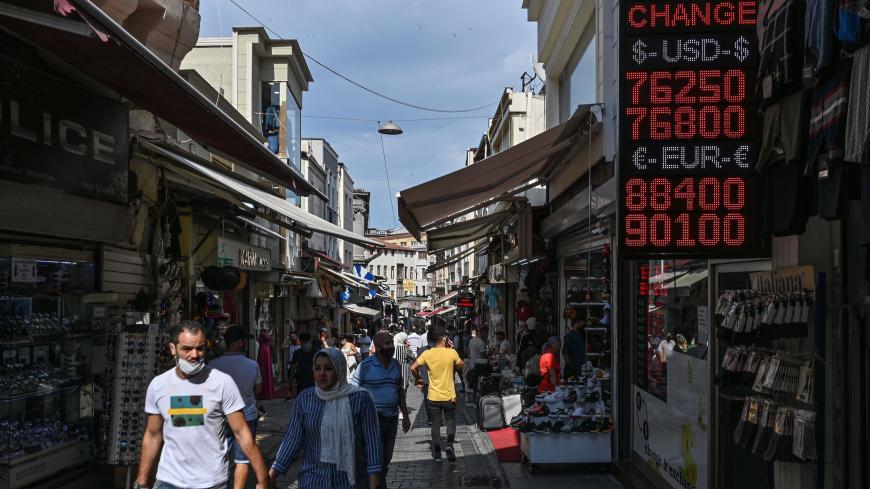 People walk past a screen showing rates at a currency exchange agency near Grand bazaar, in Istanbul, on September 24, 2020. - Turkey's central bank on September 24, 2020 raised its main interest for the first time since September 2018, boosting the rate by two percentage points to help the lira recover from historic lows. (Photo by Ozan KOSE / AFP) (Photo by OZAN KOSE/AFP via Getty Images)