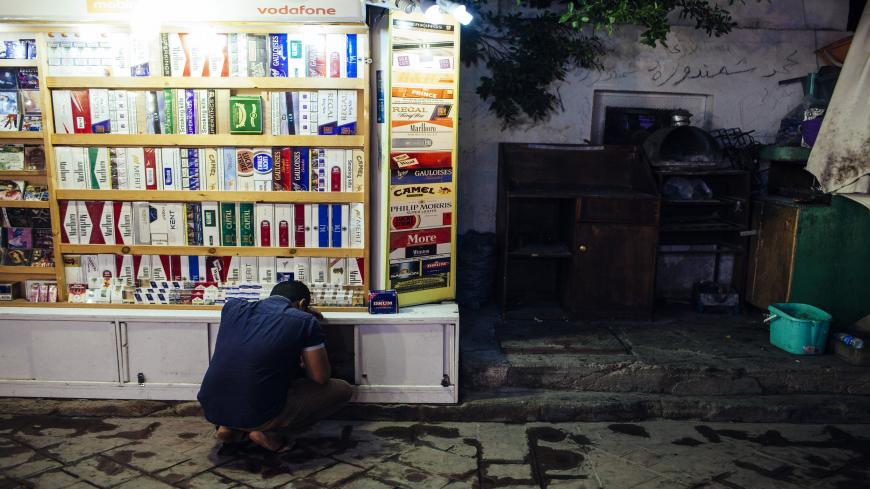 SHARM EL SHEIKH, EGYPT - OCTOBER 26: An Egyptian man kneels down at a small cigarette stall on a restaurant strip popular with tourists on October 26, 2013 in the Red Sea resort town of Sharm El Sheikh, Egypt. Sharm el-Sheikh, lying on the Red Sea coast in Egypt's South Sinai governorate, is one of Egypt's most popular destinations for tourists. Egypt's tourist industry has struggled since a popular uprising overthrew President Hosni Mubarak in early 2011, and tourist numbers have taken a further dive since