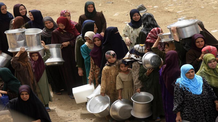 TO GO WITH AFP STORY NATASHA YAZBECK Egyptians women queue in line at a water cistern (unseen) to fill their containers with drinking water at al-Rahawe village some 40 kilometres northeast Cairo on May 27, 2010. Thousands of Egyptians living just a stone's throw from the Nile suffer supply and sanitation problems as their government becomes increasingly entangled in a war over water with up-river nations.   AFP PHOTO/KHALED DESOUKI (Photo credit should read KHALED DESOUKI/AFP via Getty Images)