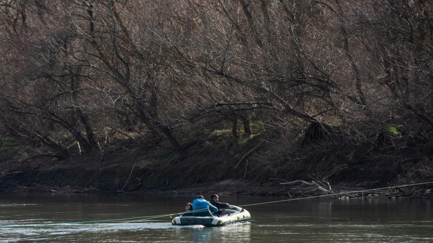 EDIRNE, TURKEY - MARCH 02: Three men hold a rope as they travel in an inflatable boat as they attempt to enter Greece from Turkey by crossing the Evros river on on March 02, 2020 in Edirne, Turkey. Thousands of refugees and migrants have flocked to the Greece, Turkey border after Turkey announced that it would open border gates for a period of 72hrs to allow refugees to cross into European countries after thirty three Turkish soldiers were killed in a Syrian air raid in Idlib. (Photo by Burak Kara/Getty Im