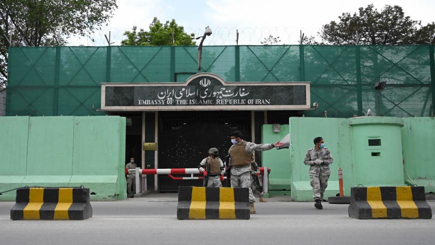 Afghan security personnel stand guard in front of the Iranian embassy as civil society activists hold banners and shout slogans against the Iranian government during a protest, in Kabul on May 11, 2020. - Afghanistan has recovered 18 bodies of migrants who were allegedly beaten and tortured before being forced into a river by Iranian border guards last week, a senior Afghan official said on May 8. Afghan authorities are investigating claims the migrants drowned while illegally crossing into neighbouring Ira