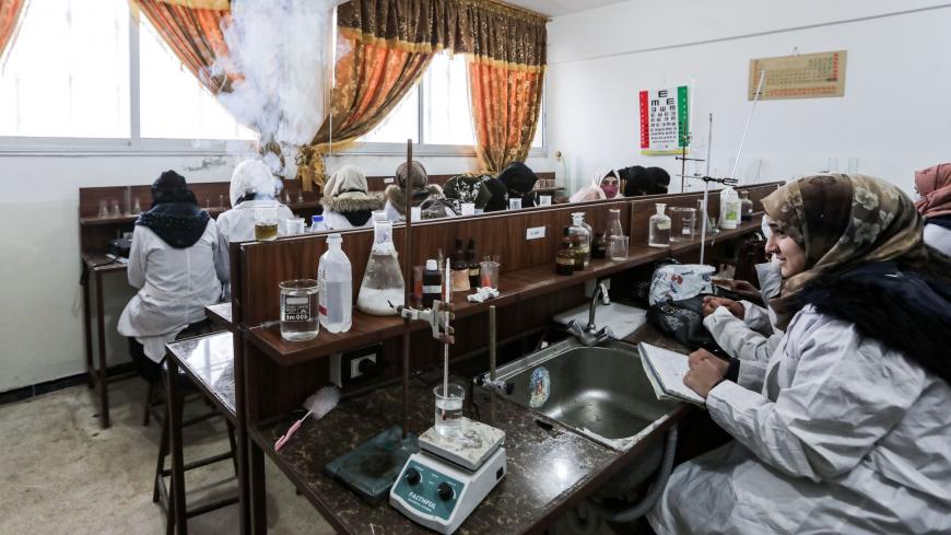 This picture taken on November 26, 2020 shows Syrian students from the "Aleppo University in Liberated Areas", controlled by the pro-Turkey opposition, attending a tutorial at a laboratory facility in Marea in the rebel-controlled northern countryside of Syria's Aleppo province, while mask-clad due to the COVID-19 coronavirus pandemic. - The university had its first batch of 32 doctors to ever graduate after its founding in 2014, headquartered in Azaz for the past three years. Humanitarian workers fear any 