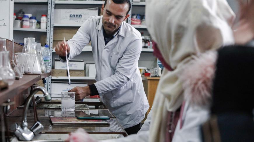 This picture taken on November 26, 2020 shows Syrian students from the "Aleppo University in Liberated Areas", controlled by the pro-Turkey opposition, attending a tutorial at a laboratory facility in Marea in the rebel-controlled northern countryside of Syria's Aleppo province, while mask-clad due to the COVID-19 coronavirus pandemic. - The university had its first batch of 32 doctors to ever graduate after its founding in 2014, headquartered in Azaz for the past three years. Humanitarian workers fear any 